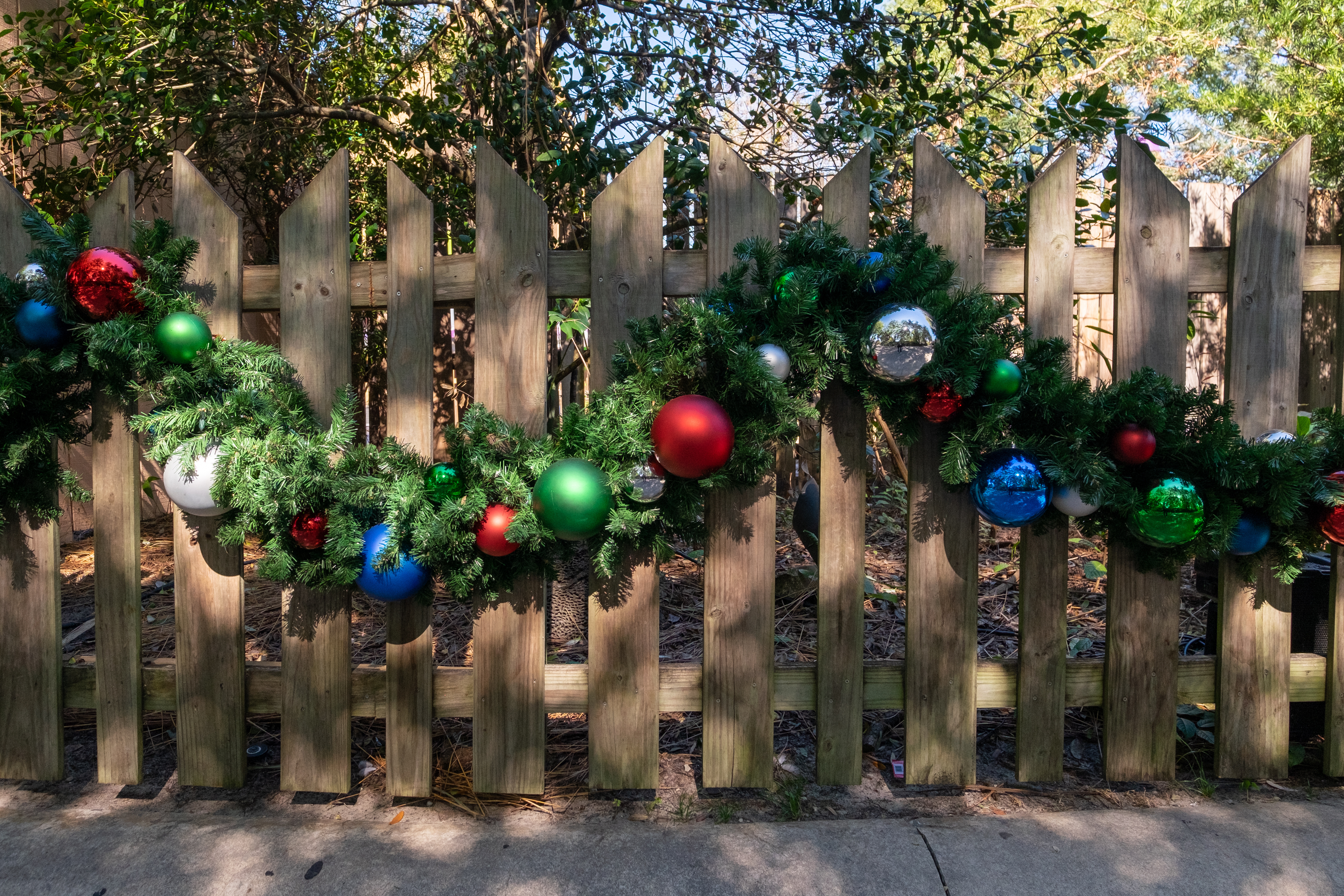 A wooden fence decorates with garland and ornaments - book with 76 FENCE, the best fence contractor in Charlotte, NC.