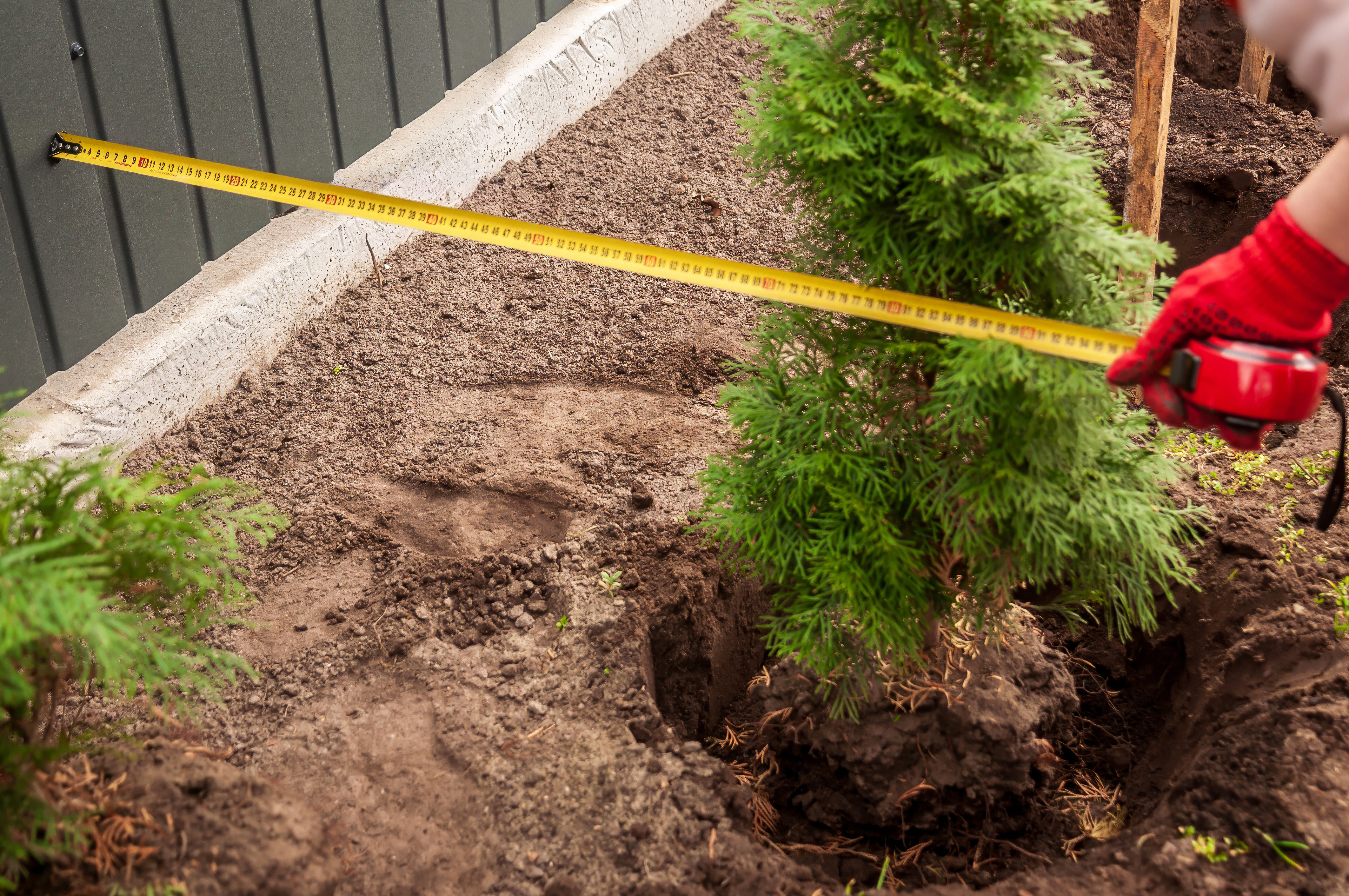 A person measuring a fence to ensure it is within a property line - contact 76 Fence today to learn more about property lines for fence projects!