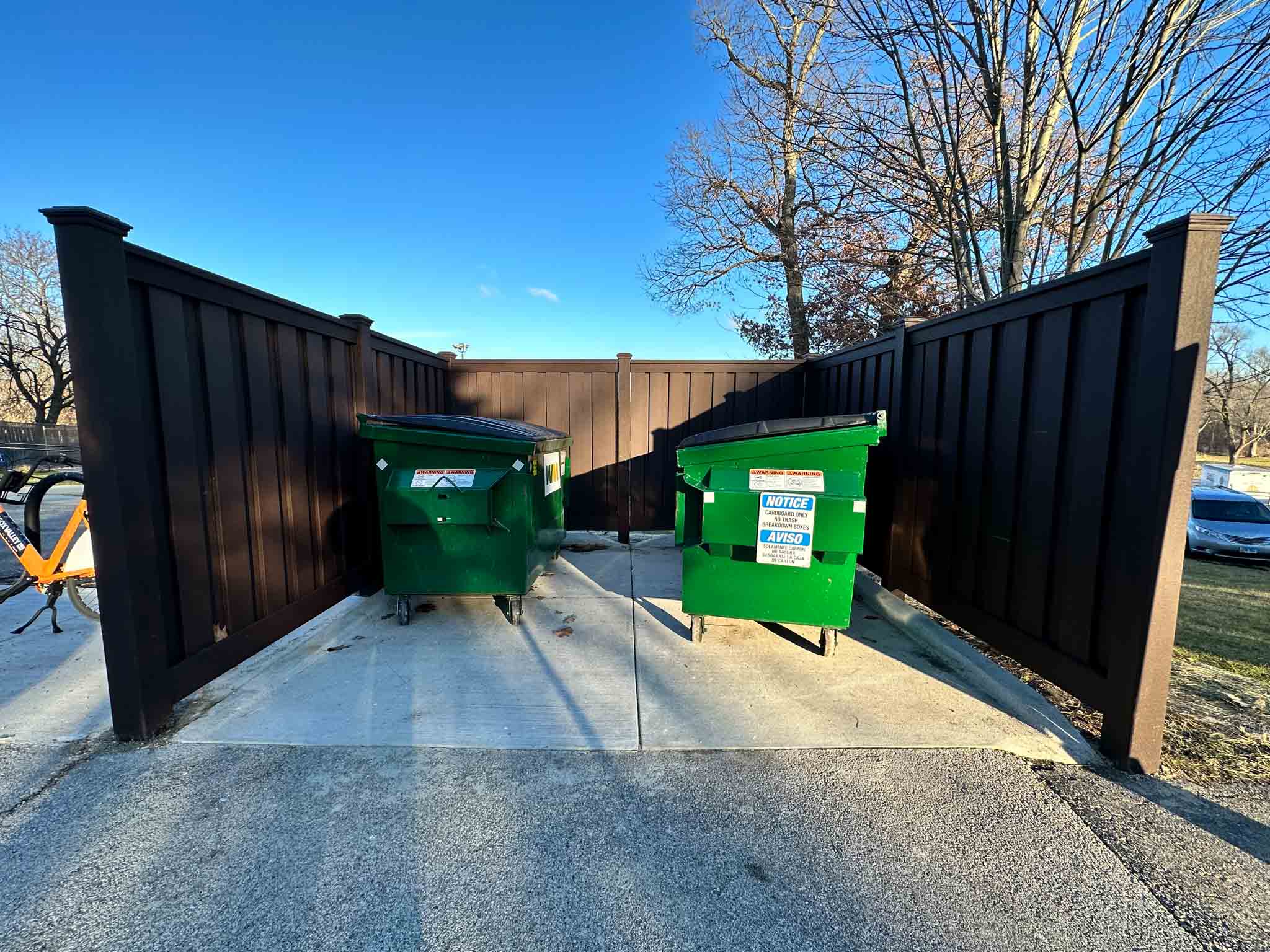 A fence surrounding a Charlotte commercial dumpster enclosure.