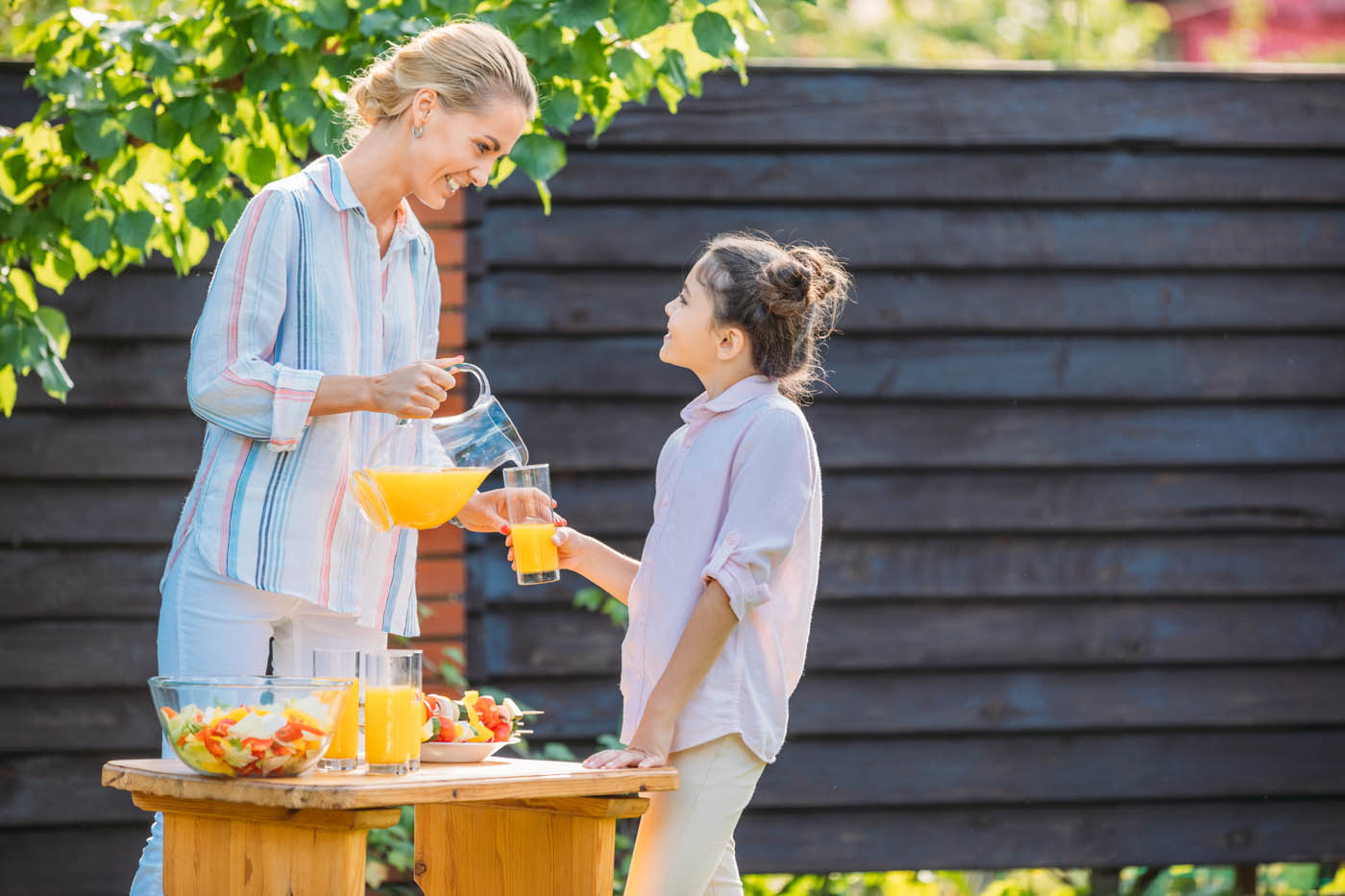 A family in a backyard enjoying the benefits of their wood fence - contact 76 FENCE's Charlotte wood fence builders to discuss your fence installation.