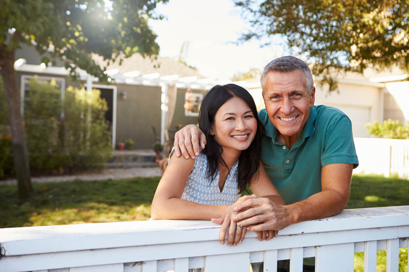 An older couple leaning against their new fence installation provided by 76 FENCE.