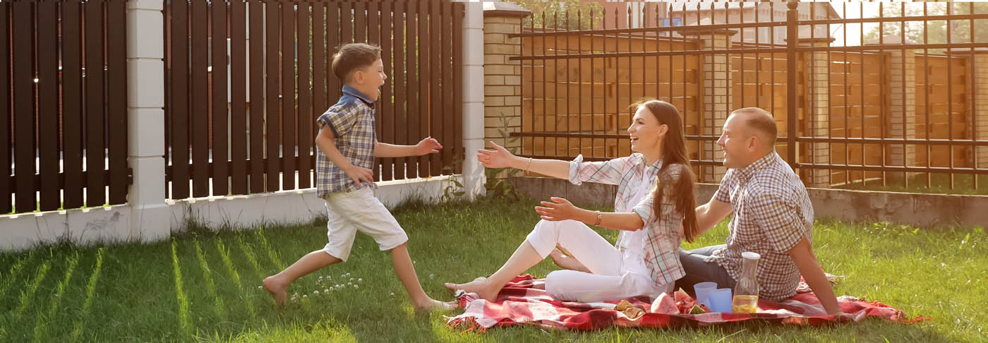 A family sitting outside in their backyard with a new fence, provided by our fencing company
				.