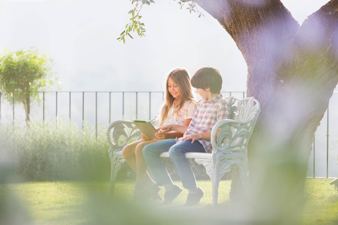 A young boy and girl sitting in a fenced in yard - Schaumburg aluminum fencing company.