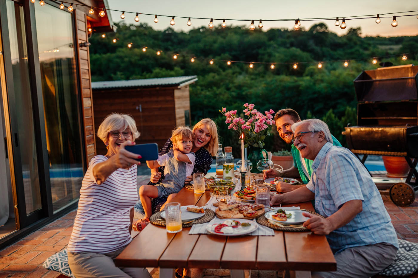 A family sitting at an outside table taking a self, 76 FENCE North Charlotte fence permitting creates a home in your backyard.