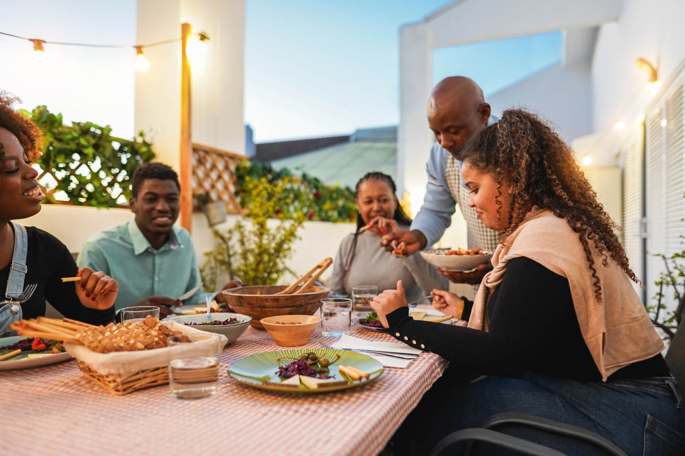 A family eating dinner outside on their deck, backyard comfort provided by 76 FENCE.