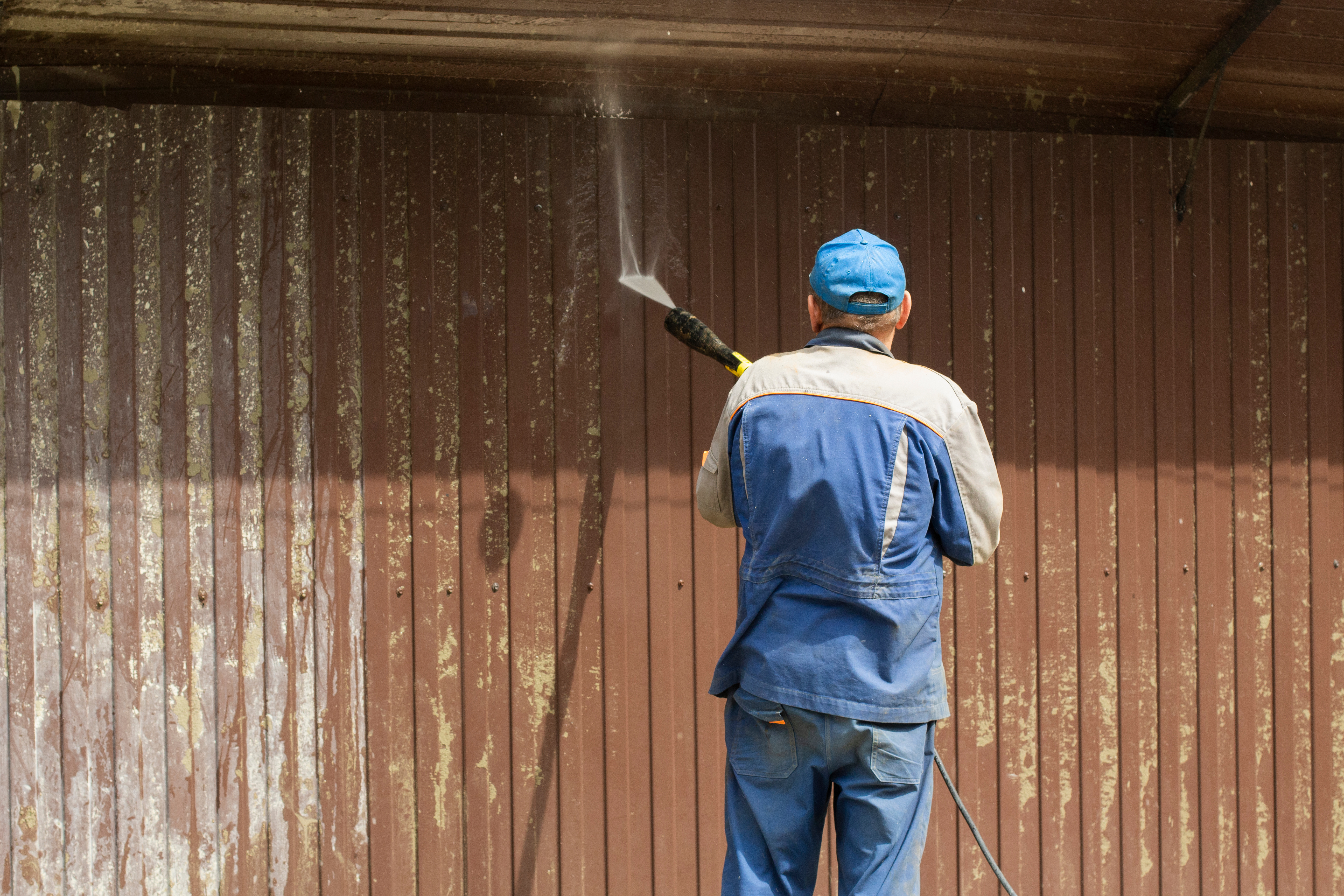 A {fran_dba) technician giving a fence a deep clean with a power wash.