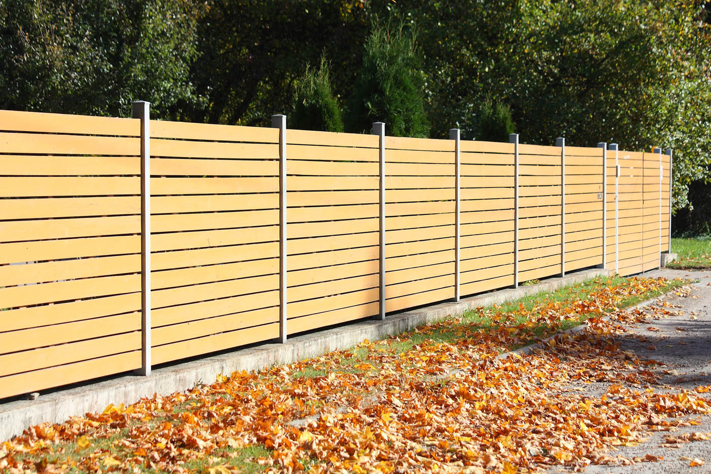 A beautiful horizontal fence with fall leaves on the ground - if you want a horizontal front yard fencecontact 76 FENCE.